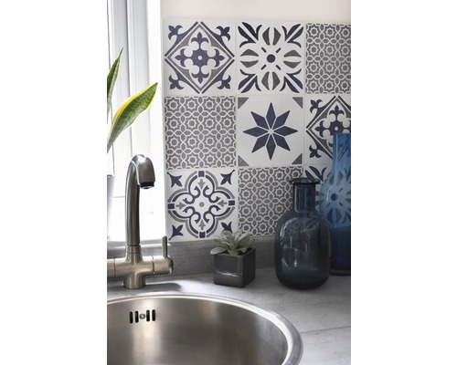 Drez s batériou pred stenou s ozdobnými obkladačkami v kuchynskej oblasti.