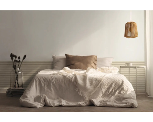 Spálňa s posteľou, vankúšmi, prikrývkou, nočným stolíkom a lampou