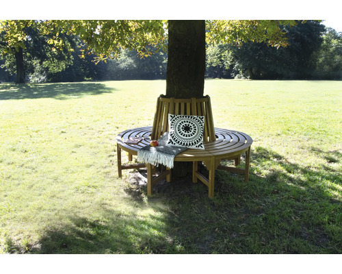 Drevená lavička okolo stromu s vankúšom a dekou v záhrade