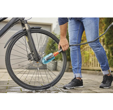 Osoba čistí bicykel kefou.