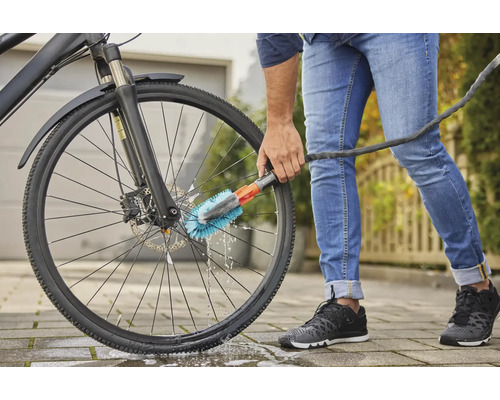 Osoba čistí bicykel kefou.