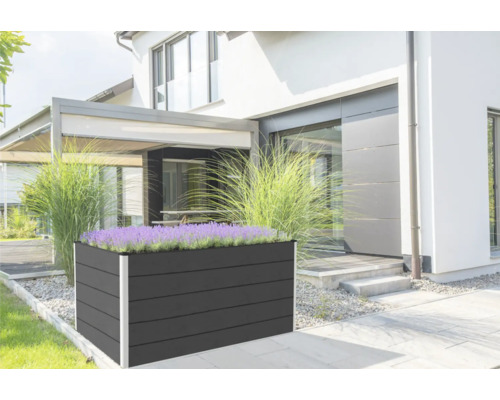 Veľký obdĺžnikový drevený vyvýšený záhon s rastlinami pred domom.