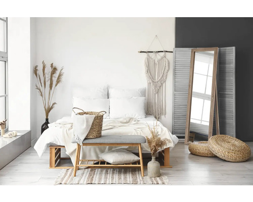 Svetlá spálňa s posteľou, zrkadlom a dekoratívnymi prvkami v bohémskom štýle