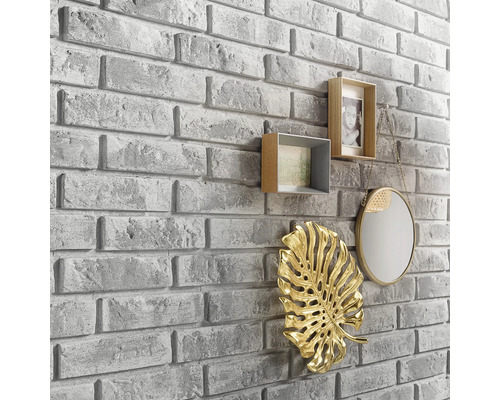 Nástenná dekorácia s kamenným vzhľadom a dekoratívnymi prvkami, ako sú rámčeky na fotografie, zrkadlo a listová ozdoba