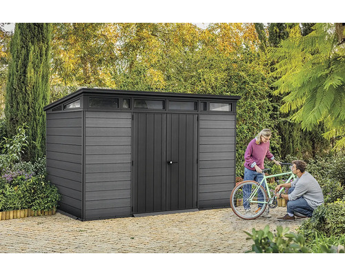 Sivá kôlňa s horným svetlom a dvoma ľuďmi opravujúcimi bicykel