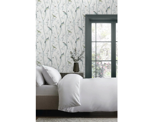Spálňa s posteľou a tapetou so vzorom vtákov a rastlín