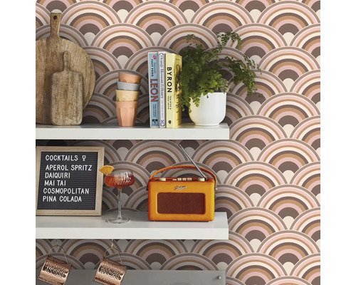 Police s doskami na krájanie, riadom, rastlinami, knihami, pohárom na koktaily, rádiom, koktailovým lístkom a tapetou s motívom oblúkov