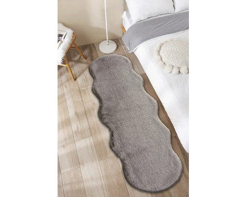 Interiérová snímka spálne s posteľou a sivým kobercom vo vzhľade kožušiny.