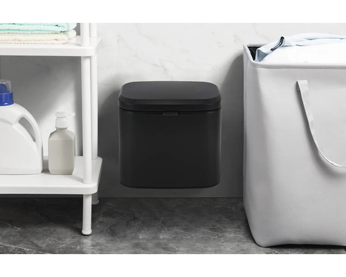 Nástenný odpadkový kôš vedľa koša na bielizeň a police