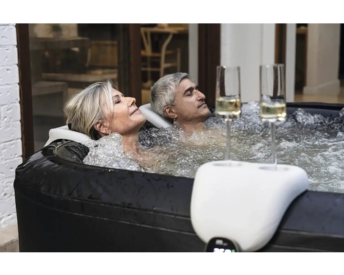 Uvoľnený pár v nafukovacej vírivke s držiakom nápojov a pohármi na šampanské