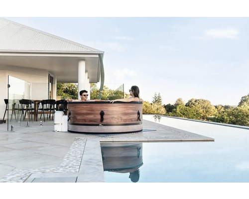 Pár relaxuje vo vírivke na terase vedľa bazéna.