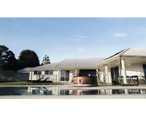 Pohľad zhora na drevenú kúpaciu kaď vedľa bazéna pred obytným domom.