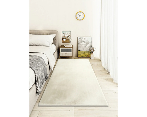 Svetlá spálňa s posteľou, nočným stolíkom a dlhým obdĺžnikovým kobercom