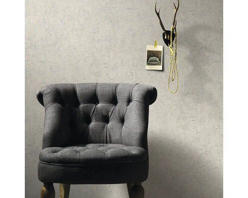 Sivé kreslo pred štruktúrovanou stenou s dekoráciou