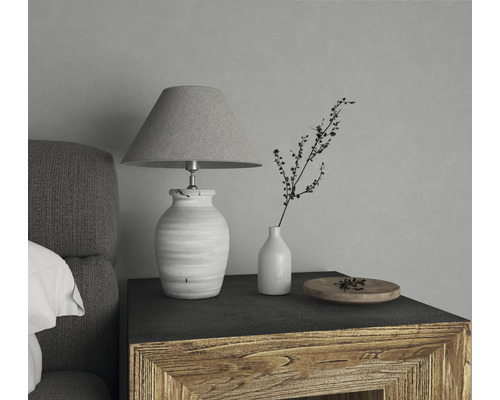 Dekoratívna stolná lampa s tienidlom vedľa vázy s vetvičkou na nočnom stolíku