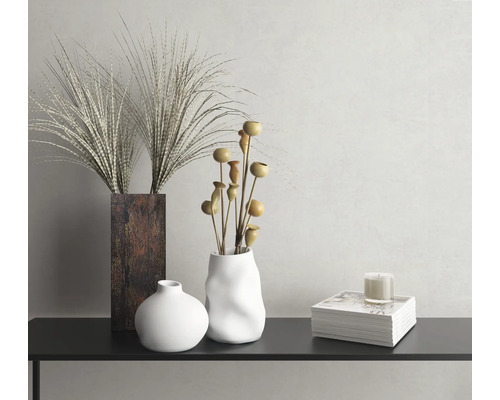 Dekoratívne zátišie s vázami, okrasnými trávami, ozdobnými vetvami a sviečkou na konzole