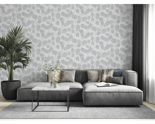 Obývacia izba so sivou pohovkou, izbovou rastlinou a tapetou s listovým vzorom