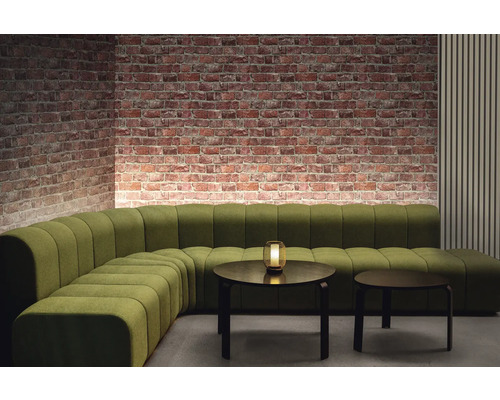 Pohľad do miestnosti so zelenou modulárnou pohovkou, dvoma okrúhlymi stolmi a tehlovou stenou