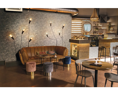 Interiér kaviarne s pohovkou, stolmi, stoličkami a nástennými svietidlami pred tehlovou stenou