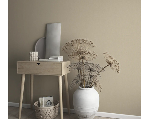 Dekoratívne aranžmán so stolíkom, vázou so sušenými kvetmi a dekoratívnymi prvkami pred jednofarebnou stenou.