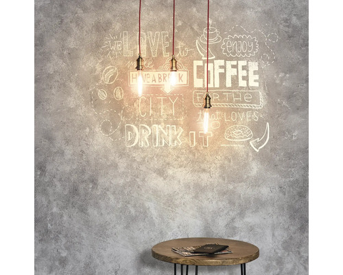 Tri závesné svetlá nad malým stolom pred stenou s motívmi kávy