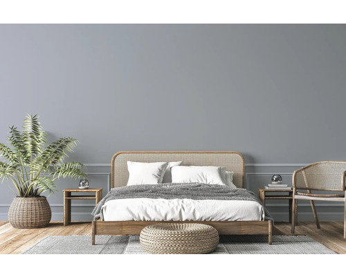 Svetlá spálňa s drevenou posteľou, prúteným nábytkom, izbovou rastlinou a kobercom