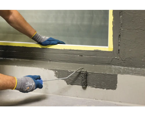 Nanášanie tesniacej malty pomocou valčeka na okenný parapet.