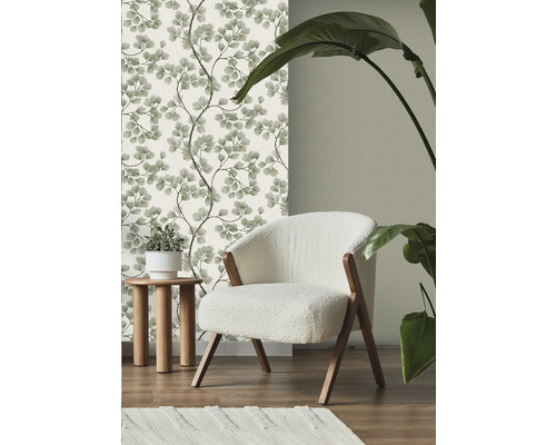 Scéna s kvetinovou tapetou, kreslom, príručným stolíkom, kobercom a izbovou rastlinou.