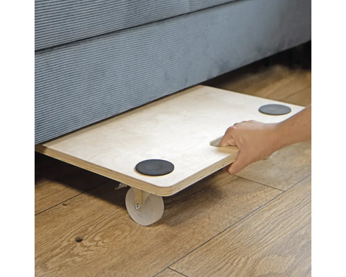 Nábytkové kolieska pod pohovkou s rukou na drevenej podlahe