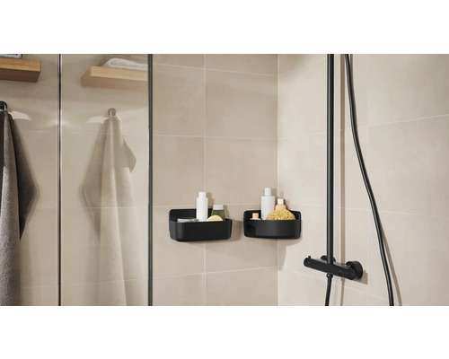 Kúpeľňa so sprchou, uterákmi a dvoma čiernymi sprchovými košmi na uloženie kúpeľňových potrieb