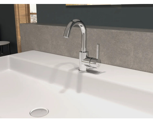 Na umývadle je lesklá vodovodná batéria.