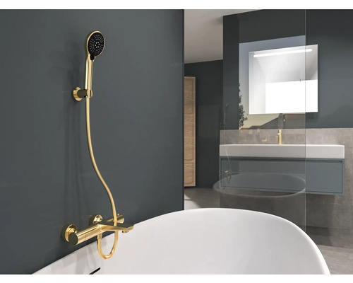 Kúpeľňa s vaňou, umývadlom a zlatou sprchovou batériou.