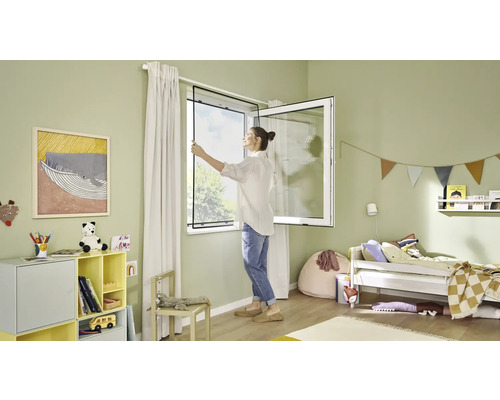 Žena montuje sieť proti hmyzu na okno v detskej izbe