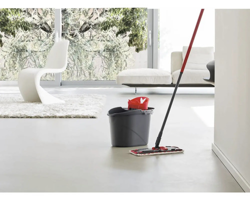 Mop s vedrom na čistenie podláh v jasnej obývacej izbe.