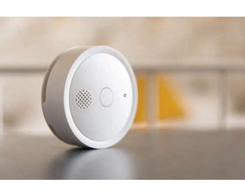 Kruhový hlásič dymu s testovacím tlačidlom a mriežkou reproduktora.