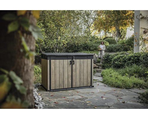 Záhradná skriňa na náradie s dreveným efektom a žena v pozadí v záhradnej krajine