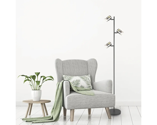 Obývacia izba s kreslom, príručným stolíkom, izbovou rastlinou a stojacou lampou s tromi reflektormi