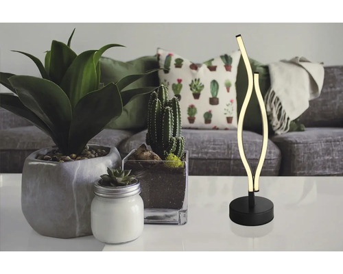Dekoratívna LED stolná lampa na stole s izbovými rastlinami a pohovkou