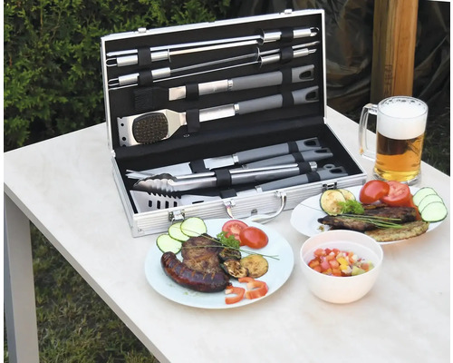 Sada grilovacieho náčinia v kufríku s pripraveným jedlom a pohárom piva na stole