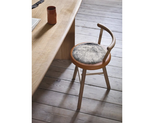 Drevená stolička s kožušinovým vankúšom pri stole