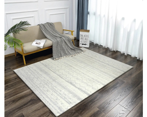 Obývacia izba s pohovkou, ozdobným vankúšom a vzorovaným kobercom na drevenej podlahe.