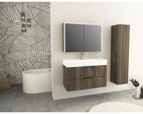 Kúpeľňa s umývadlom, zrkadlovou skrinkou a vysokou skrinkou vo vzhľade dreva pred stenou s motívom listov