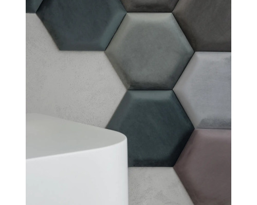 Detailný záber na šesťhranné stenové panely zo zamatu v rôznych odtieňoch šedej a biely, valcovitý príručný stolík.