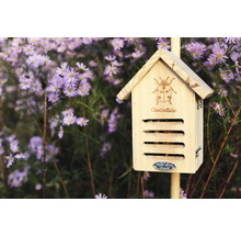 Drevený hmyzí hotel s dizajnom lienky pred kvetmi