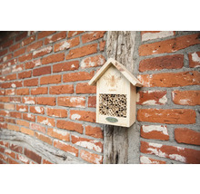 Hmyzí hotel z dreva s bambusovými rúrkami na tehlovej stene