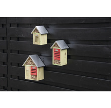 Tri drevené hotely pre hmyz s kovovou strechou na plote