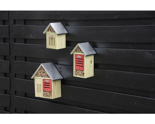 Tri drevené hotely pre hmyz s kovovou strechou na plote