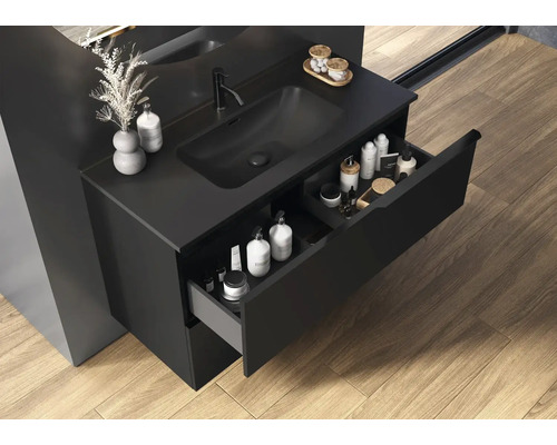 Kúpeľňa s čiernou skrinkou pod umývadlo, otvorenou zásuvkou a produktmi starostlivosti