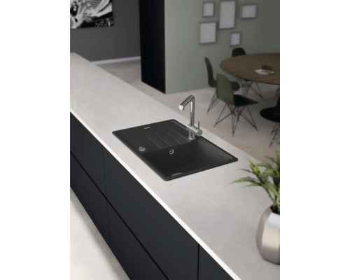 Čierny drez s vodovodnou batériou na kuchynskej linke.