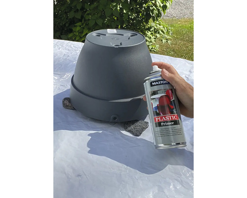 Osoba strieka kvetináč plastovým základným náterom.